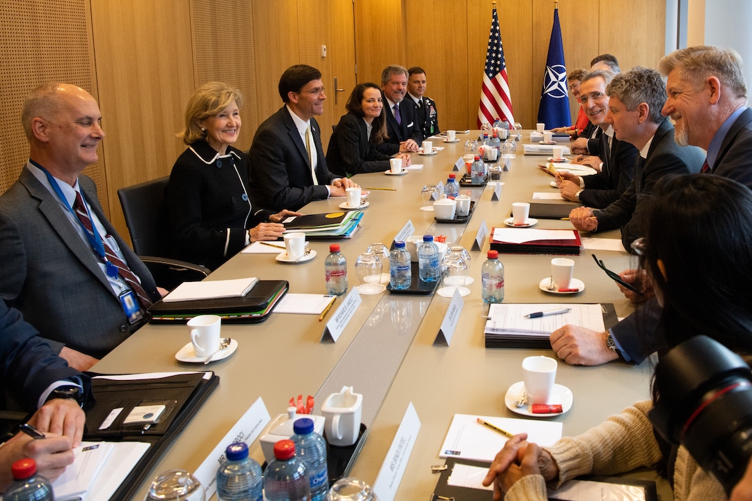 A group of men and women sit around a long table.