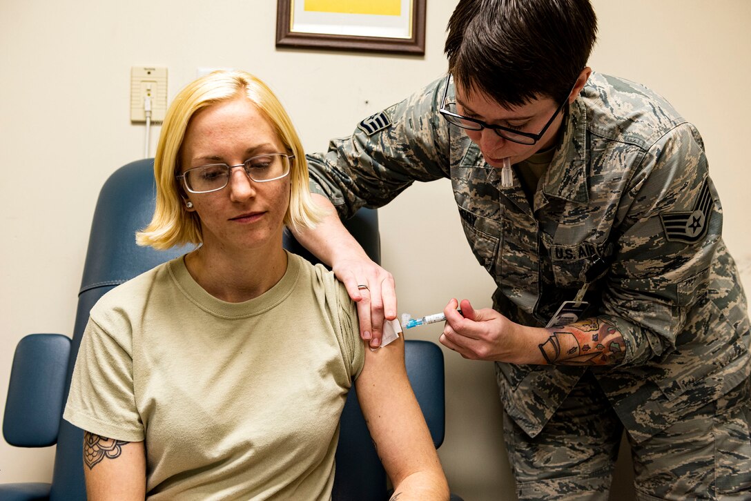 Photo of an immunizations technician giving an immunization shot to an Airman.