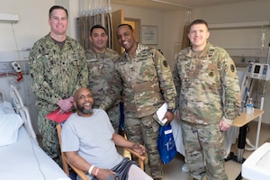 Military members of DLA Troop Support pose with a veteran patient at the Corporal Michael J. Crescenz Veterans Affairs Medical Center, Feb. 10, 2020 in Philadelphia.