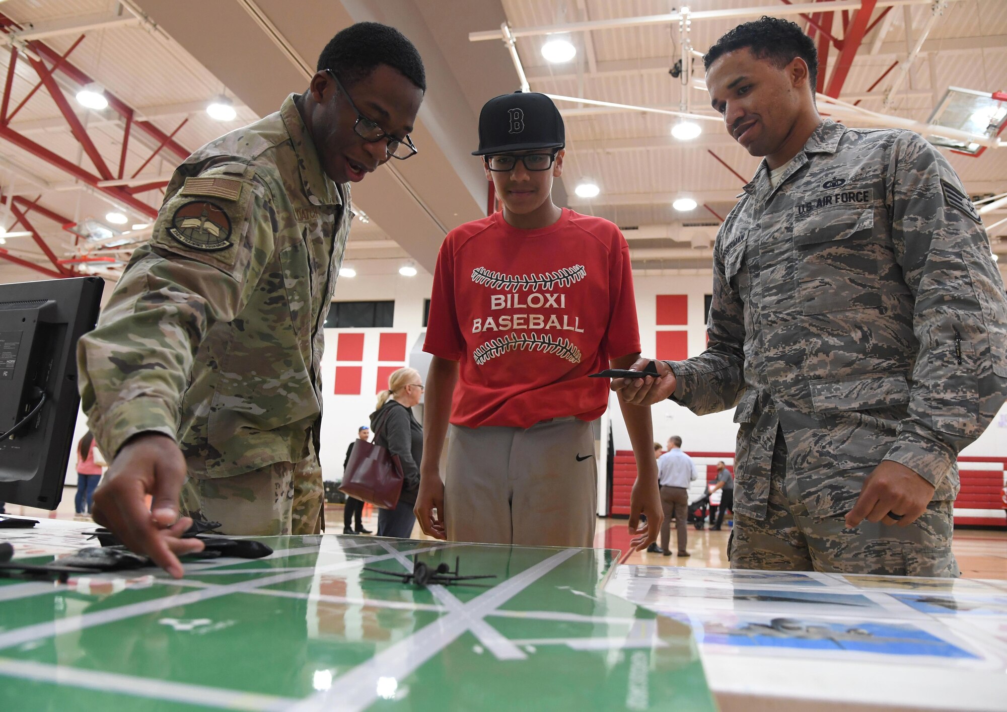 U.S. Air Force Staff Sgts. Nathaniel DeLoatch and LeAnthony Bosserman, 334th Training Squadron instructors, provide Carlos Hurtado, Jr., Biloxi Junior High School student, with an air traffic control training demonstration during the Biloxi Science, Technology, Engineering and Mathematics Night at the Biloxi Jr. High School gymnasium, Biloxi, Mississippi, Feb. 11, 2020. The entire Biloxi school district was invited to the event which promoted STEM. Seven career fields from Keesler's 81st Training Wing and the 81st Training Group participated in the event. (U.S. Air Force photo by Kemberly Groue)