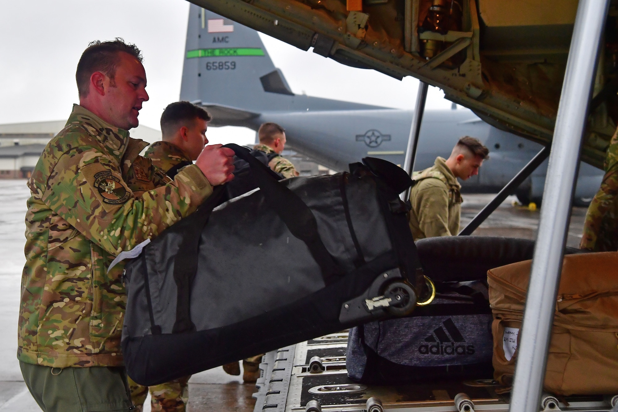 Airmen from the 61st Airlift Squadron load bags onto a C-130J Super Hercules.