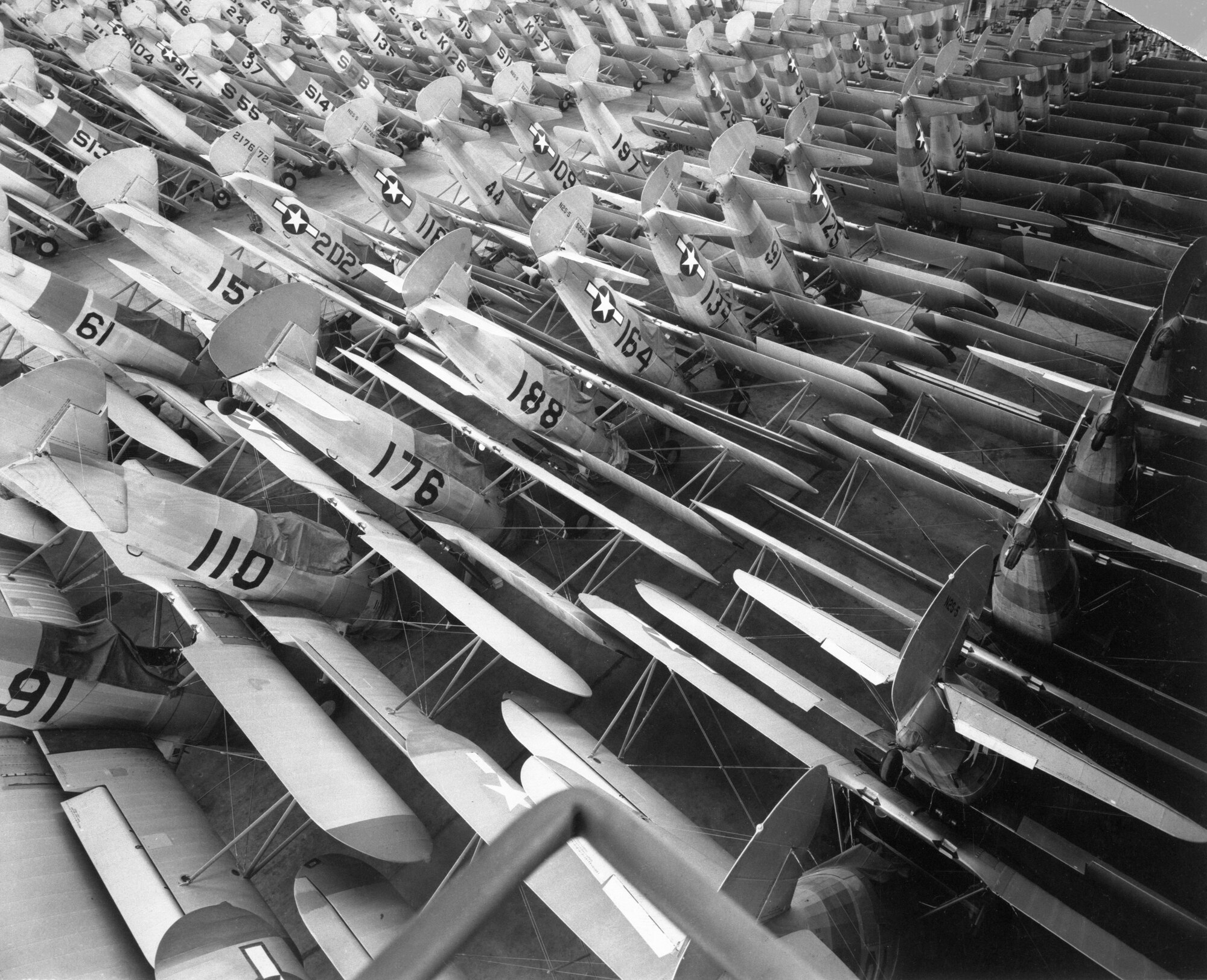 Dozens of PT-13 aircraft are stacked like books, nose-to-nose and tail-to-tail.