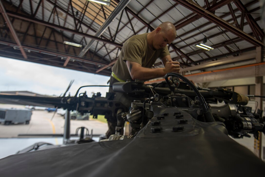 A photo of an Airman unscrewing a helicopter part.