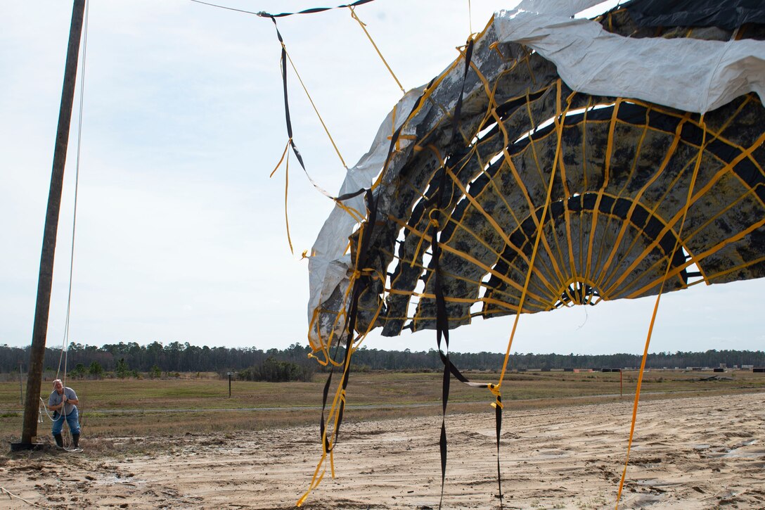 Photo of a range operator hoisting a drogue parachute.
