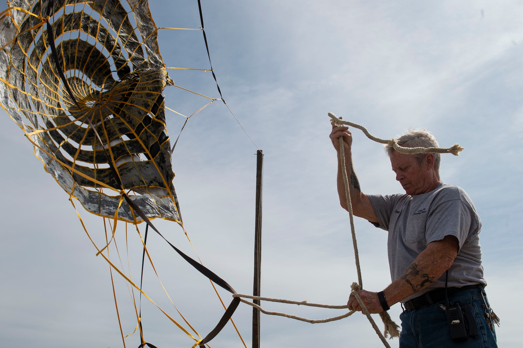 Photo a range site manager, secures a drogue parachute to a pole.