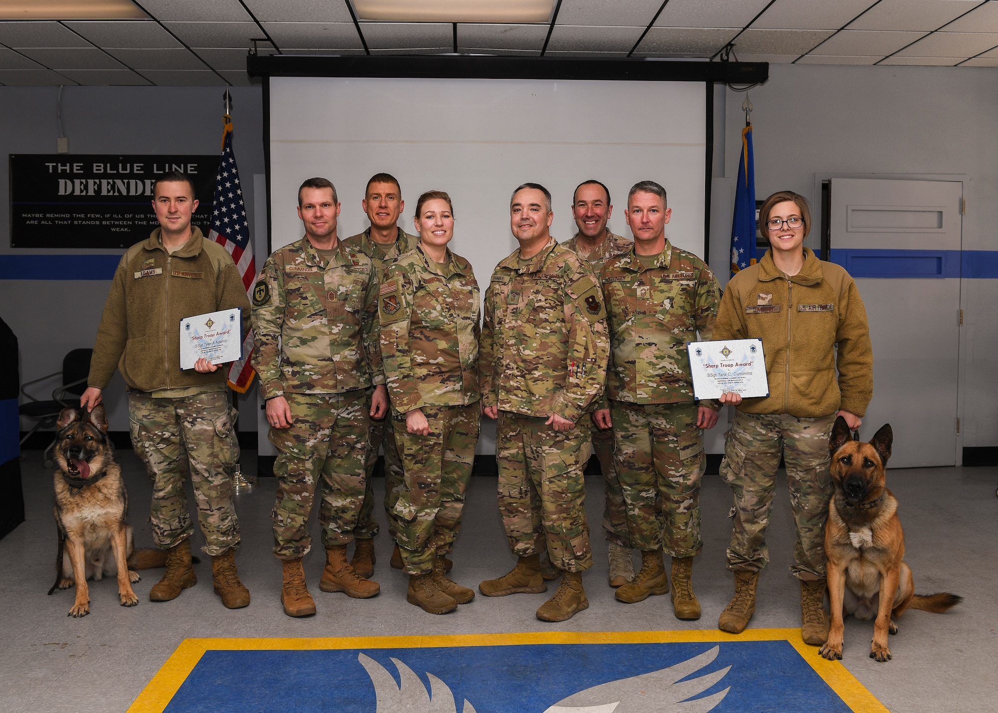Group photo of military working dogs with their handlers along with others.