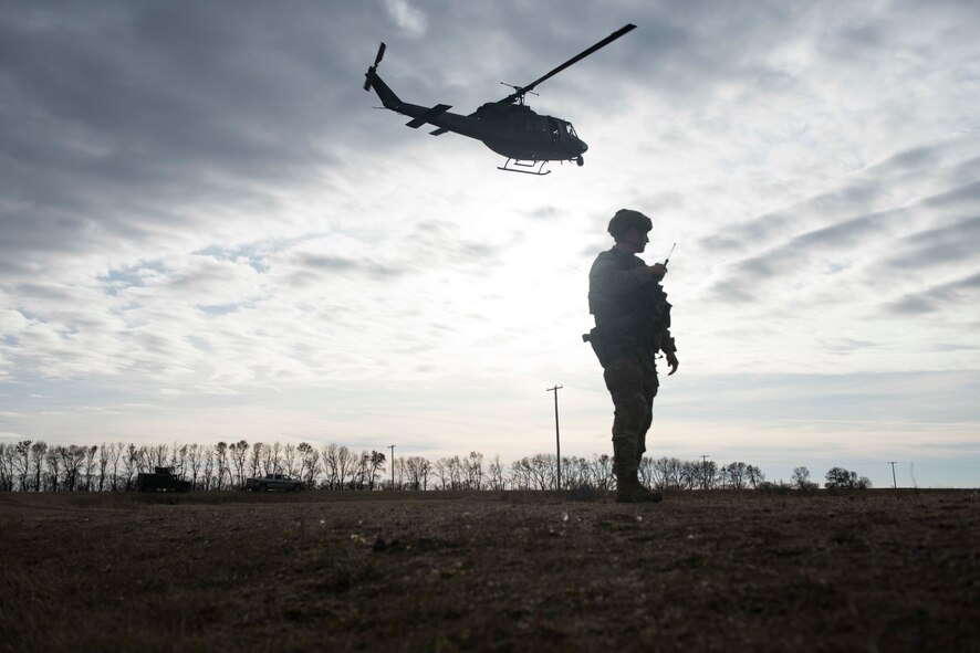 A security forces defender provides ground support guidance for a helicopter landing.