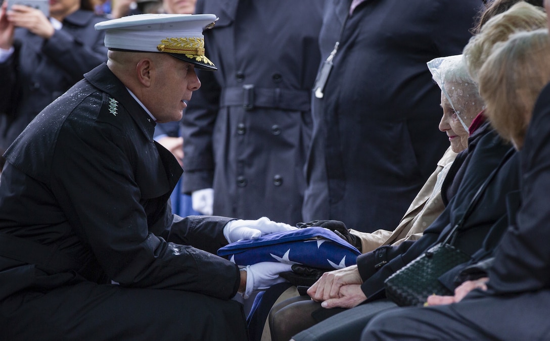 Commandant of the Marine Corps (CMC) Gen. David H. Berger presents an American flag to Barbara Kelley, wife of retired Commandant of the Marine Corps (CMC) Gen. Paul X. Kelley, at Arlington National Cemetery in Arlington, Va., Feb. 13, 2020. Kelley served as CMC from 1983 to 1987. (U.S. Marine Corps photo by Lance Cpl. Morgan L. R. Burgess)