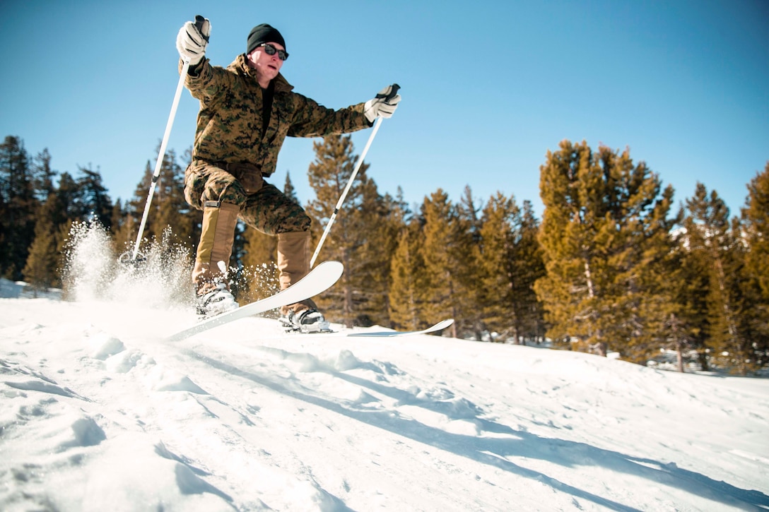 A Marine skis down a snowy slope with trees in the background.