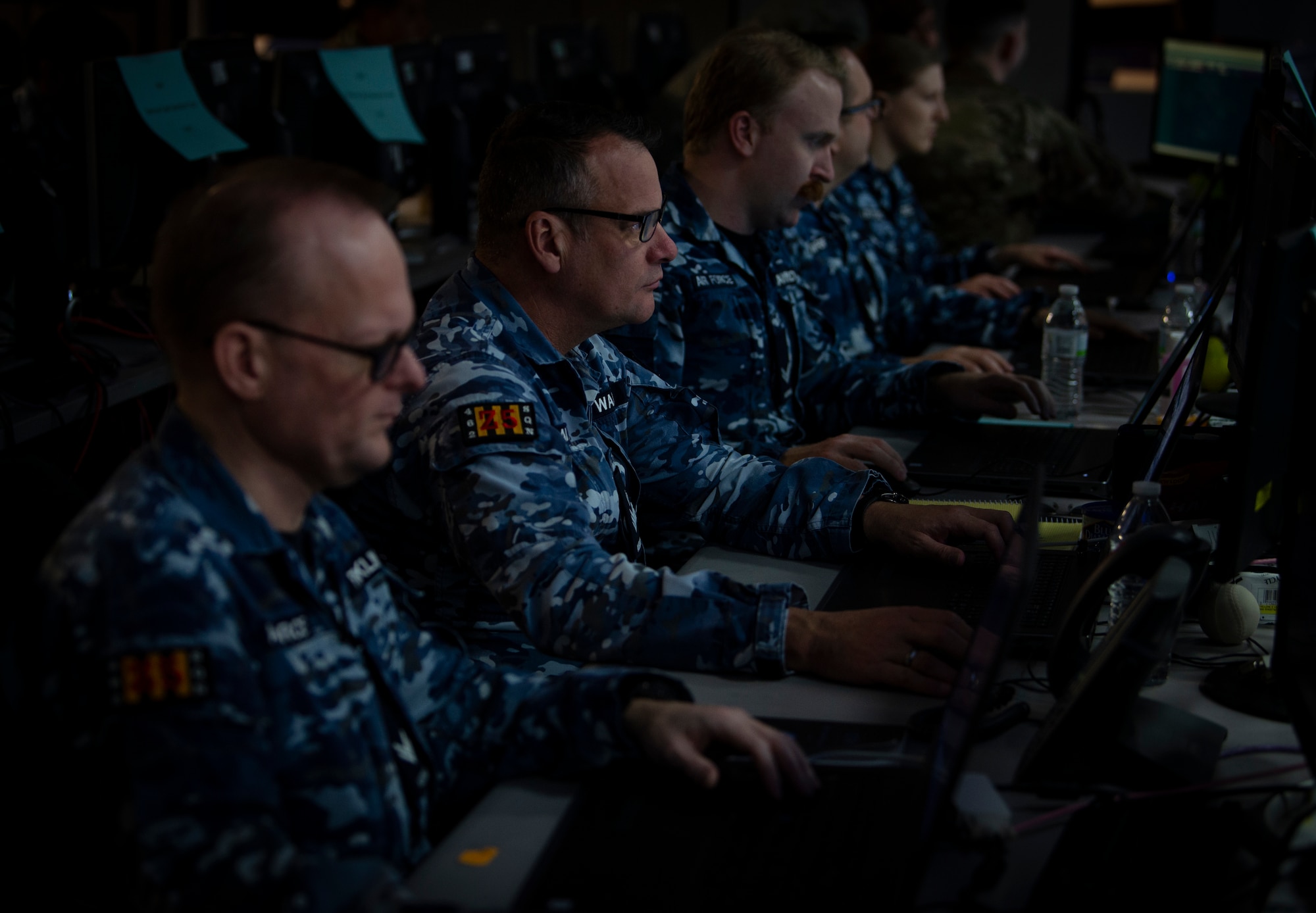 Royal Australian Air Force (RAAF) members look at computer screens.