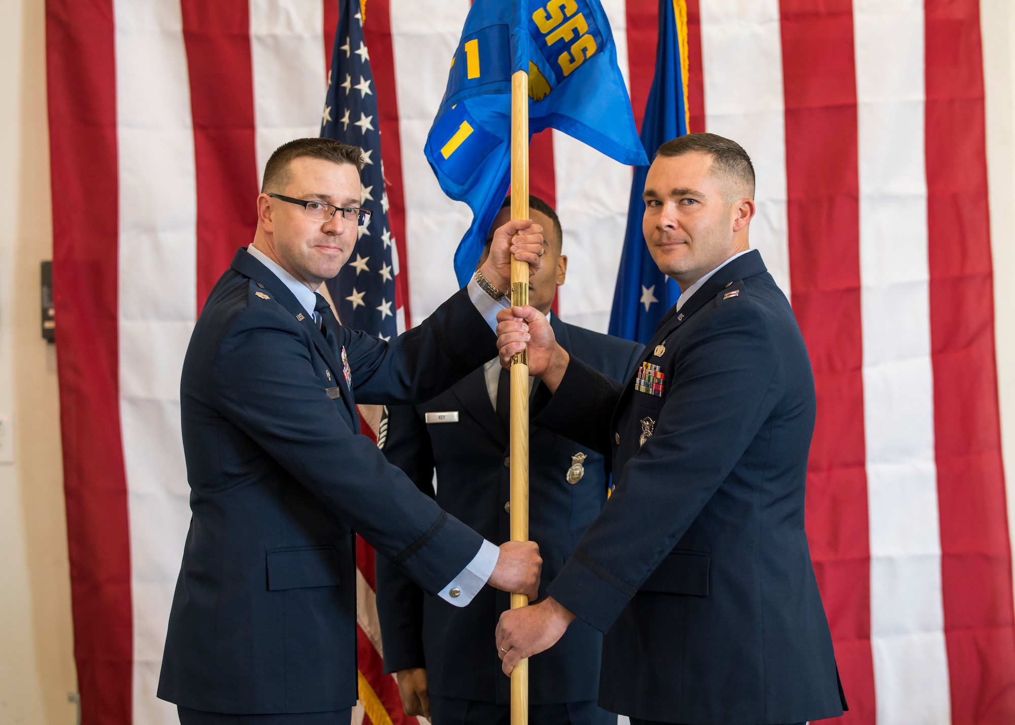 Lt. Col. Joseph Bincarousky, 412th Security Forces Squadron Commander, hands Detachment 1’s guidon to Capt. Daniel Parsons signifying his assumption of command and activation of the unit at 412th Test Wing Operation Location Plant 42 in Palmdale, California, Feb. 13. (Air Force photo by Giancarlo Casem)