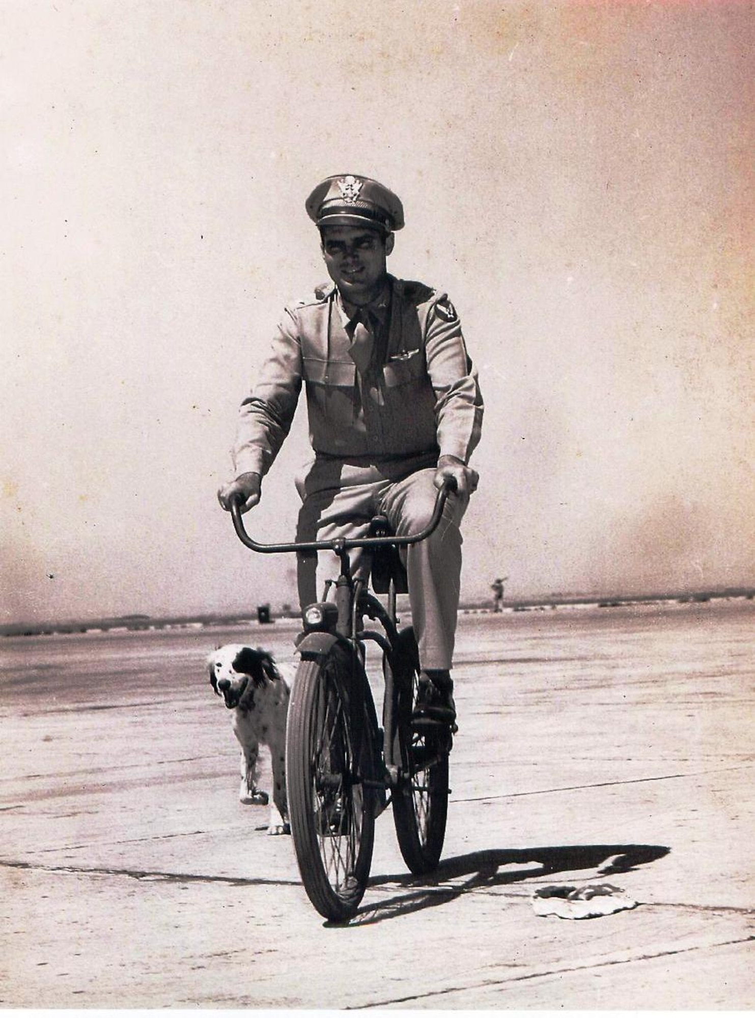 Brig. Gen. Robert Travis, 9th Heavy Bombardment Wing commander, rides his bike to work followed by his dog, Dan, at Fairfield-Suisun Air Force Base, California. Travis was killed when his B-29 Superfortress crashed Aug. 5, 1950. The base was renamed in his honor one year later. (U.S. Air Force photo)