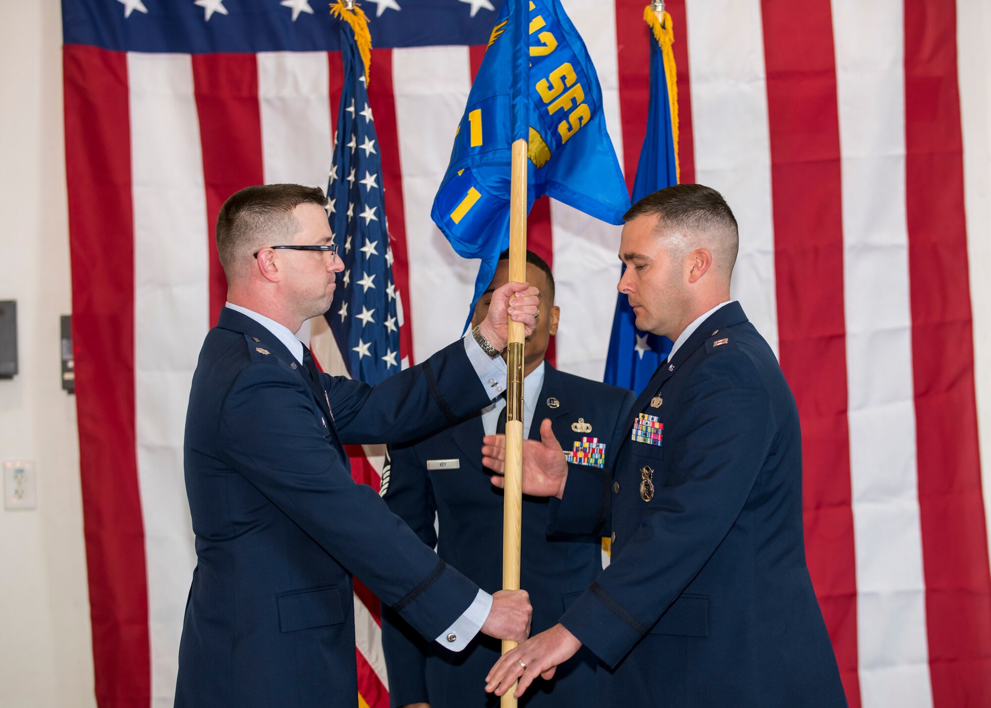Lt. Col. Joseph Bincarousky, 412th Security Forces Squadron Commander, hands Detachment 1’s guidon to Capt. Daniel Parsons signifying his assumption of command and activation of the unit at 412th Test Wing Operation Location Plant 42 in Palmdale, California, Feb. 13. (Air Force photo by Giancarlo Casem)