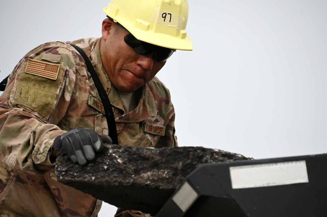 Photo of Airman moving asphalt.