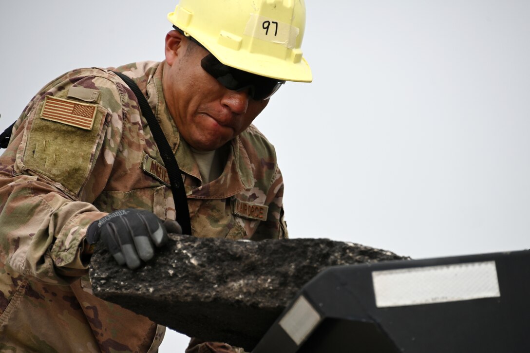 Photo of Airman moving asphalt.