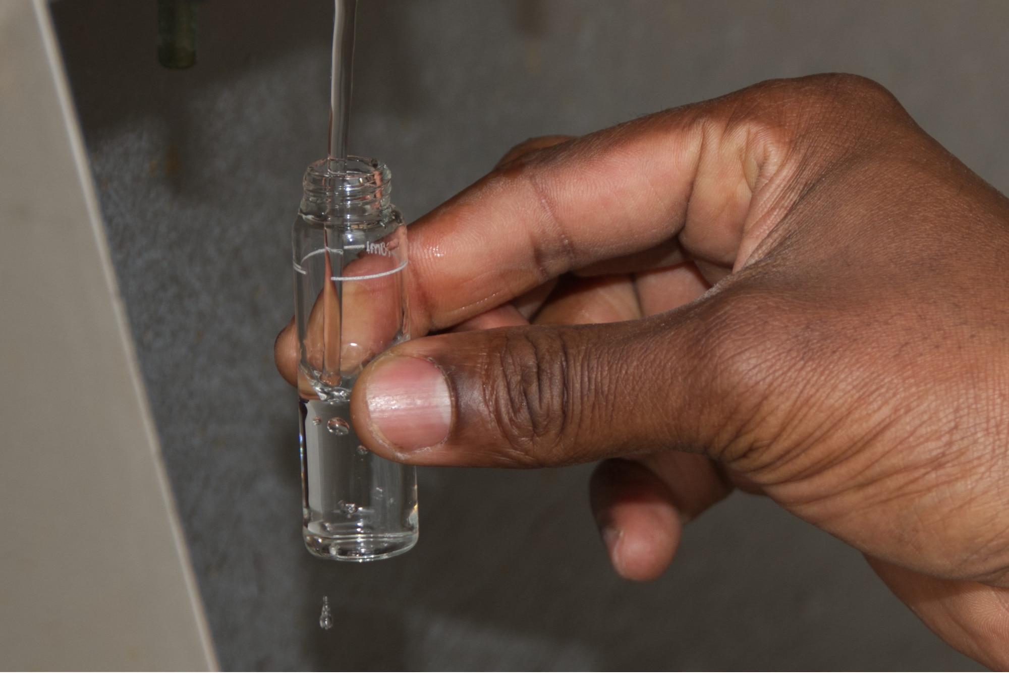 Close up photo of water dripping from water sample bottle.