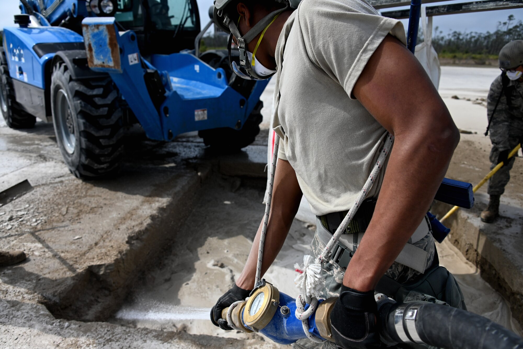 Photo of Airman adding water to concrete mix.