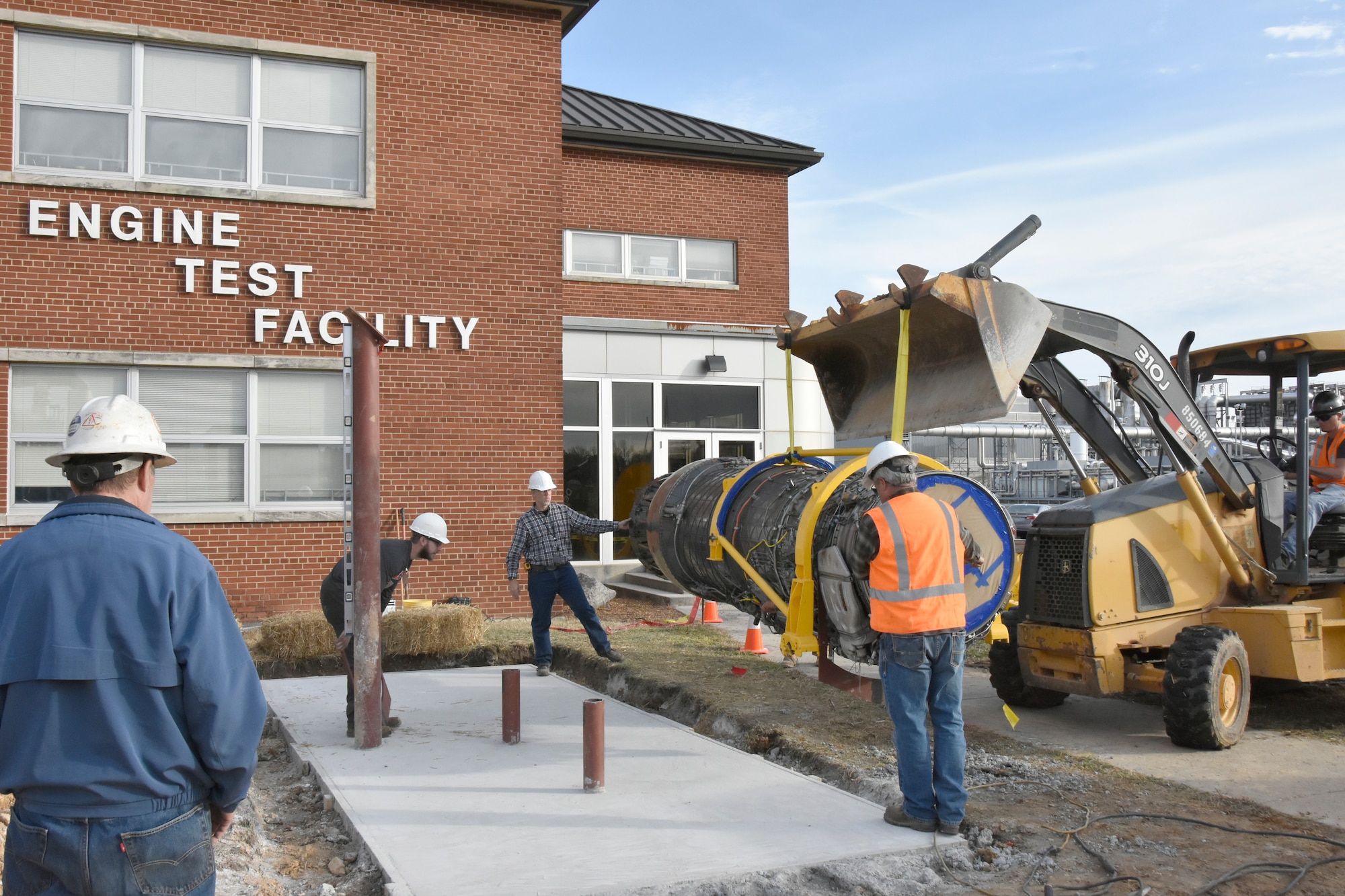 Workers with Henley Construction and Welding Unlimited install an F100 engine for display outside of the Engine Test Facility at Arnold Air Force Base. The installation of the display was completed in late 2019 and coincided with the 50th anniversary of the first operation at Arnold AFB involving the F100, which occurred on Dec. 18, 1969. Since then, Arnold Engineering Development Complex has logged over 23,000 hours testing the F100 series of engines in numerous test facilities. (U.S. Air Force photo by Bradley Hicks) (This image was altered by obscuring badges for security purposes.)
