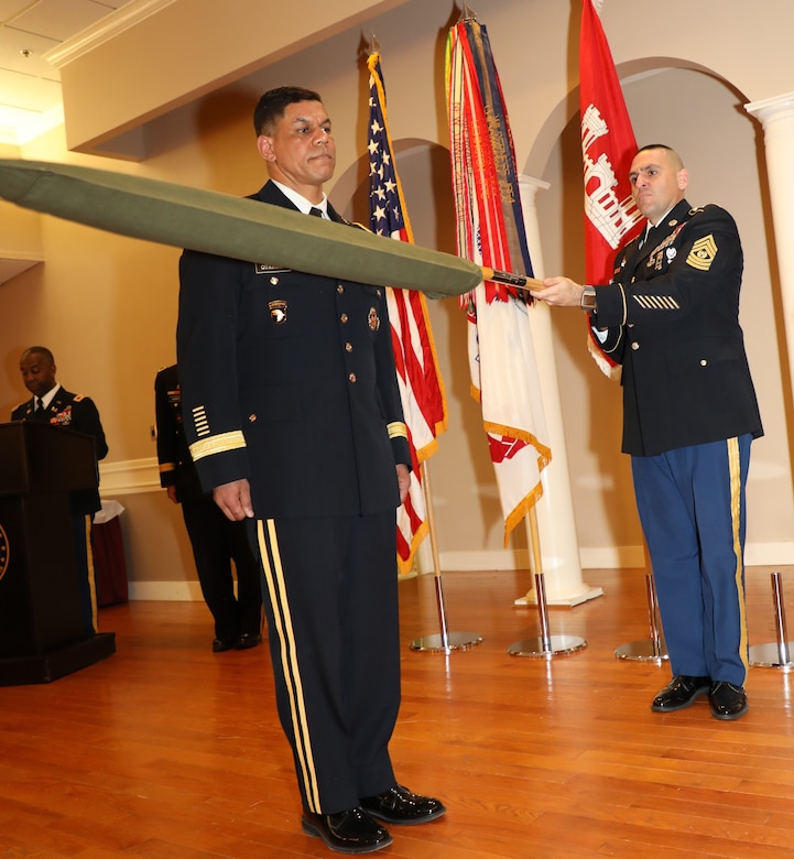 Transatlantic Division Command Sergeant Major Randolph Delapena assists Brig. Gen. Quander in uncasing and unfurling the one-star flag representative of an army brigadier general. All general officers are issued a flag embroidered in the center with their rank. The flag, when displayed, signifies a general's presence. Delapena’s participation in the ceremony also represented the enlisted rank and signified the senior enlisted advisor as the keeper of the colors for military officers.