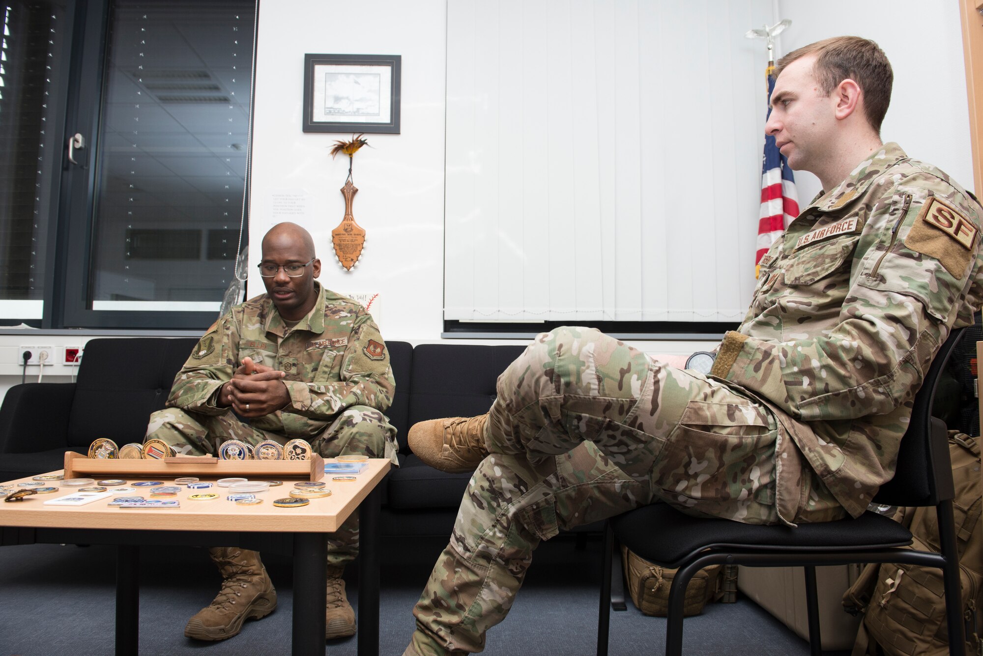 Photo of two Airmen conversing at a table