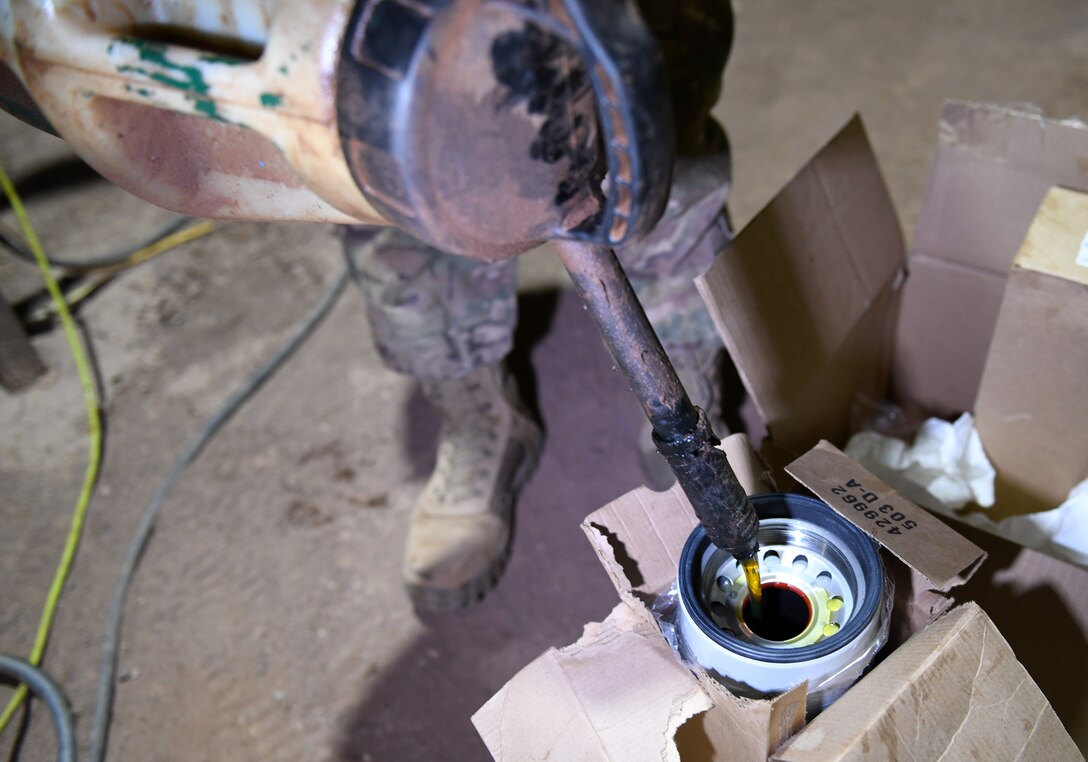 Photo of Airmen performing preventative maintenance on a generator.