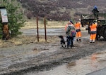 People and dogs make there way to a military cargo truck with flood waters near by.