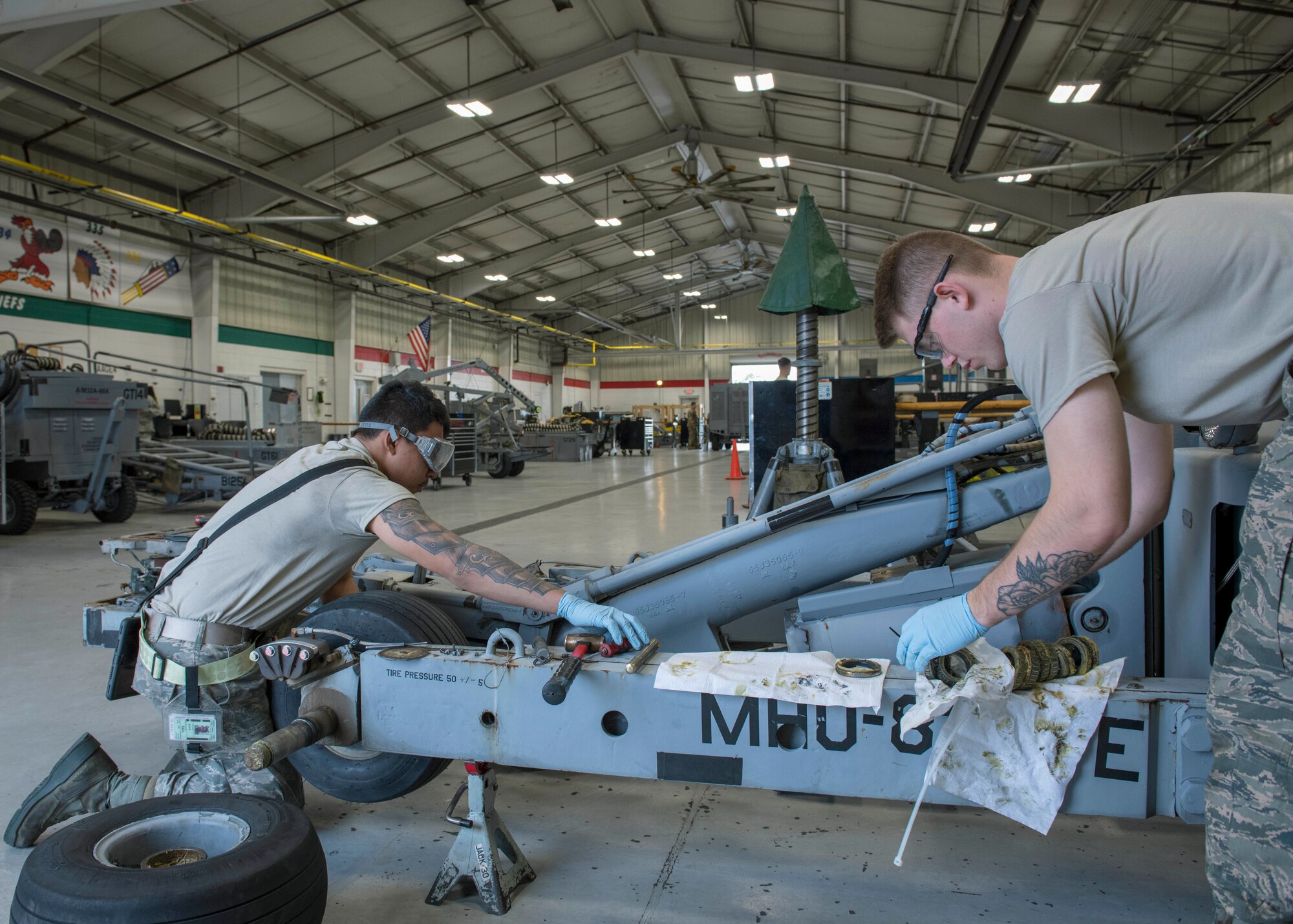 Airman 1st Class Mathew Castro, 4th Equipment Maintenance aerospace ground equipment apprentice (left), and Airmen 1st Class Drennon Hausman, 4th Equipment Maintenance aerospace ground equipment apprentice (right), clean the wheel bearings on an MHU-83 bomb lift truck, Feb. 4, 2020, at Seymour Johnson Air Force Base, N.C.