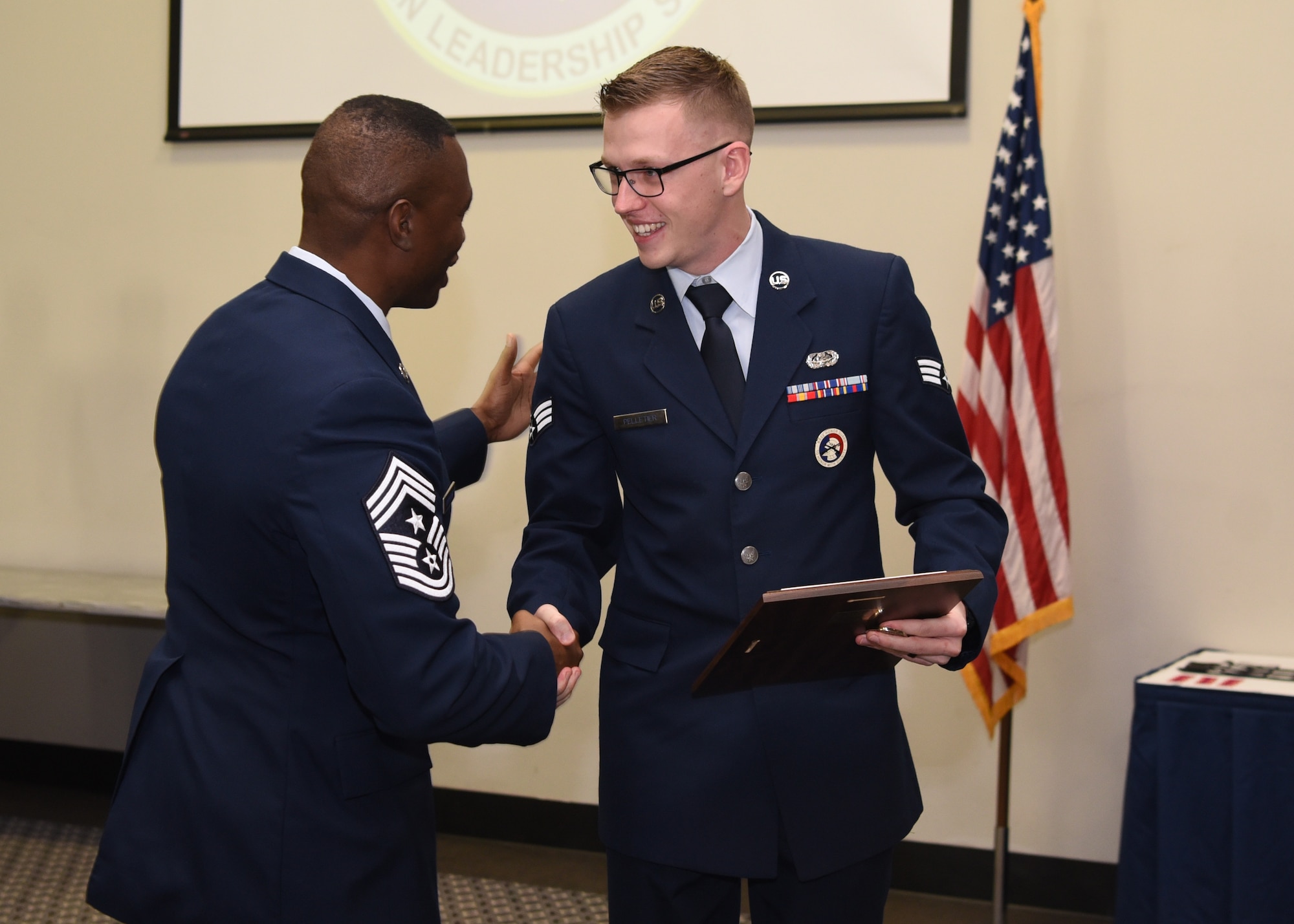 U.S. Air Force Chief Master Sgt. Lavor Kirkpatrick, 17th Training Wing command chief, gives Senior Airman Quinten Pelletier, 17th Force Support Squadron base honor guard program manager, a congratulatory coin during the Airman Leadership School Graduation Ceremony in the event center at Goodfellow Air Force Base, Texas, Feb. 13, 2020. Pelletier was awarded the Commandant award for denoting excellent leadership as identified by peers and ALS staff. (U.S. Air Force photo by Airman 1st Class Abbey Rieves