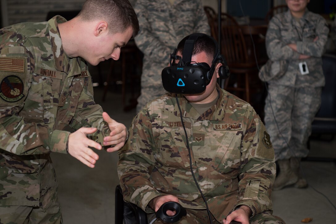 (Left) U.S. Air Force Senior Airman Ronald Randall, 547th Intelligence Squadron instructor, Nellis Air Force Base, Nevada, helps (right) Senior Airman Joshua Little, 1st Operations Support Squadron intel analyst, use a virtual reality system brought to Joint Base Langley-Eustis, Virginia, by Airmen from the 547th IS, Feb. 12, 2020.