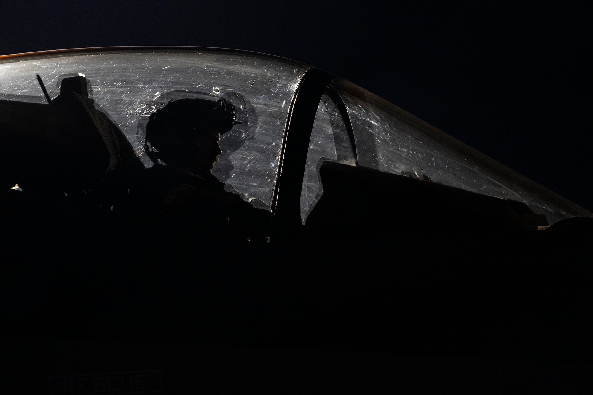 An F-35A Lightning II fighter jet pilot sits in the cockpit of an F-35A at night.