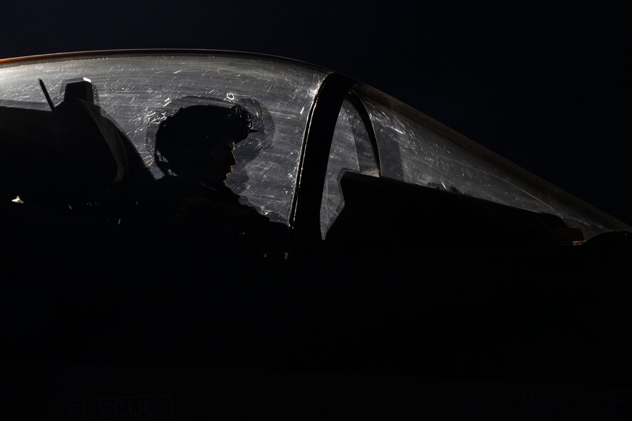 An F-35A Lightning II fighter jet pilot sits in the cockpit of an F-35A at night.
