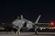 An F-35A Lightning II fighter jet prepares for take-off at night.