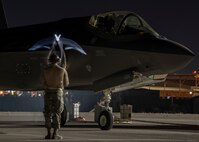 An Airman signals an F-35A Lightning II fighter jet pilot at night.