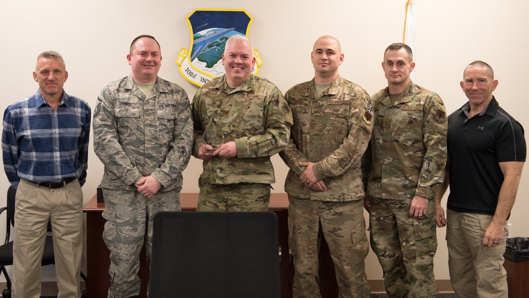 A group of military and civilian Airmen celebrate the wing's winning of the 2019 Air National Guard, Director of Safety Award for Outstanding Achievement in Occupational Safety by posing with the award.
