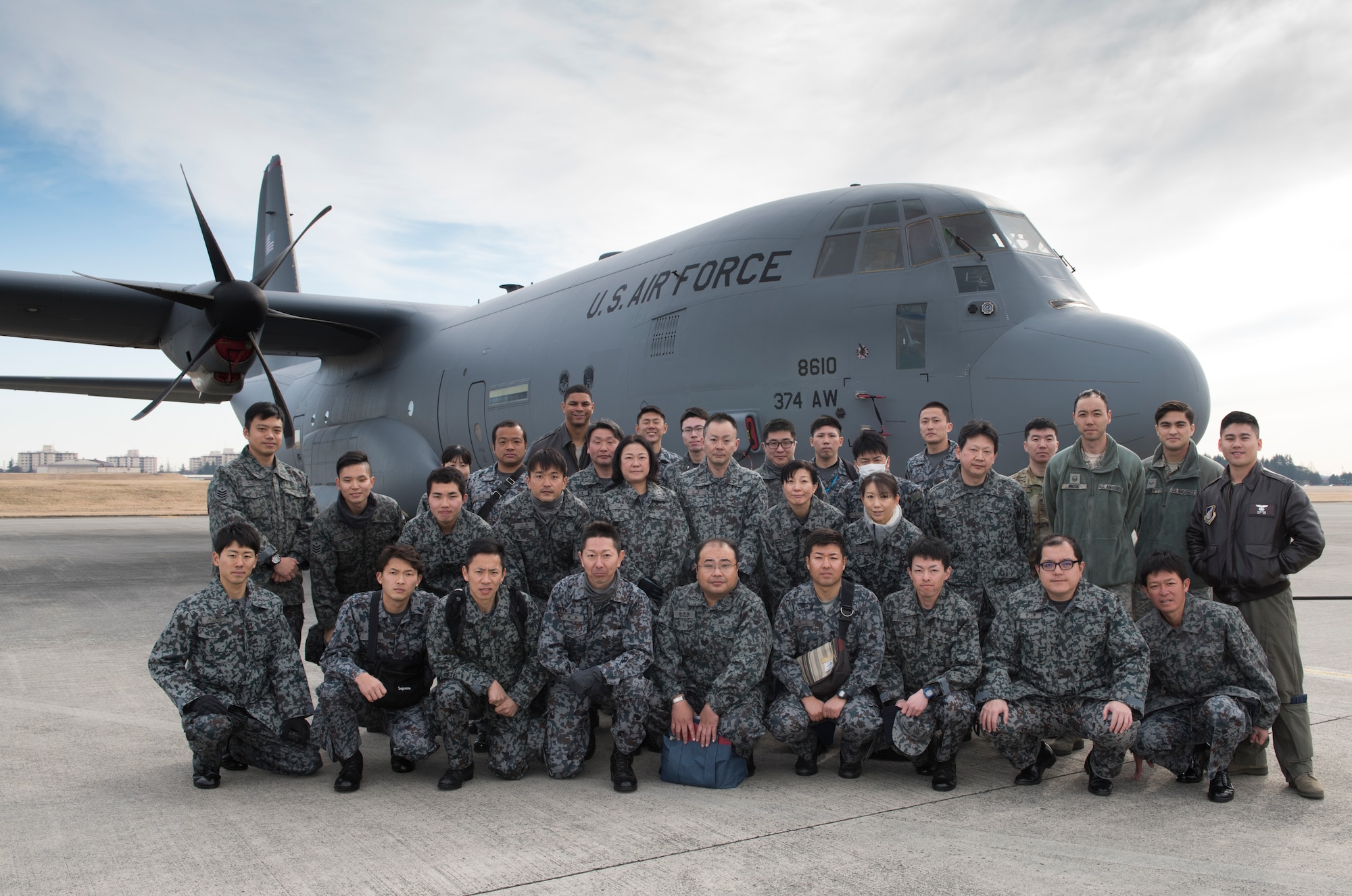 U.S. Air Force and Japan Air Self-Defense Force members pose for a photo in front of a C-130J Super Hercules during a tour at Yokota Air Base, Japan, Feb.12, 2020.