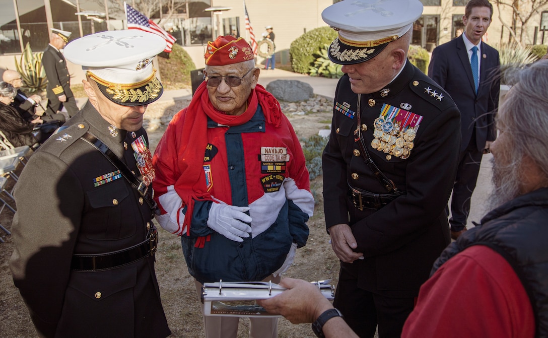 Iwo Jima Marine veteran Thomas H. Begay, center, a Navajo Code Talker, shares his scrapbook of photos from his time as a Marine to Lt. Gen. Joseph L. Osterman, right,  commanding general of I Marine Expeditionary Force, and Maj. Gen. Robert F. Castellvi, left, commanding general of 1st Marine Division, before the start of the 75th Commemoration of the Battle of Iwo Jima sunset ceremony at Marine Corps Base Camp Pendleton, California, Feb. 15.