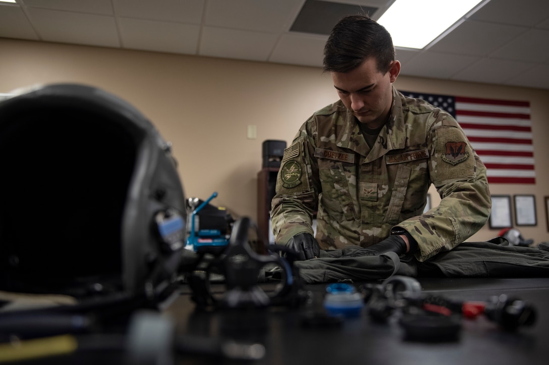 A photo of an Airman waxing an Anti-G suit zipper during an inspection.