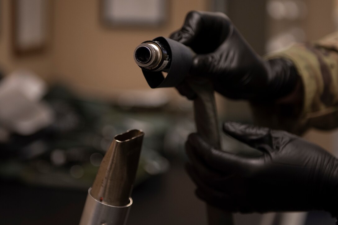 A photo of an Airman warming up a heat shrink on an Anti-G suit during an inspection.