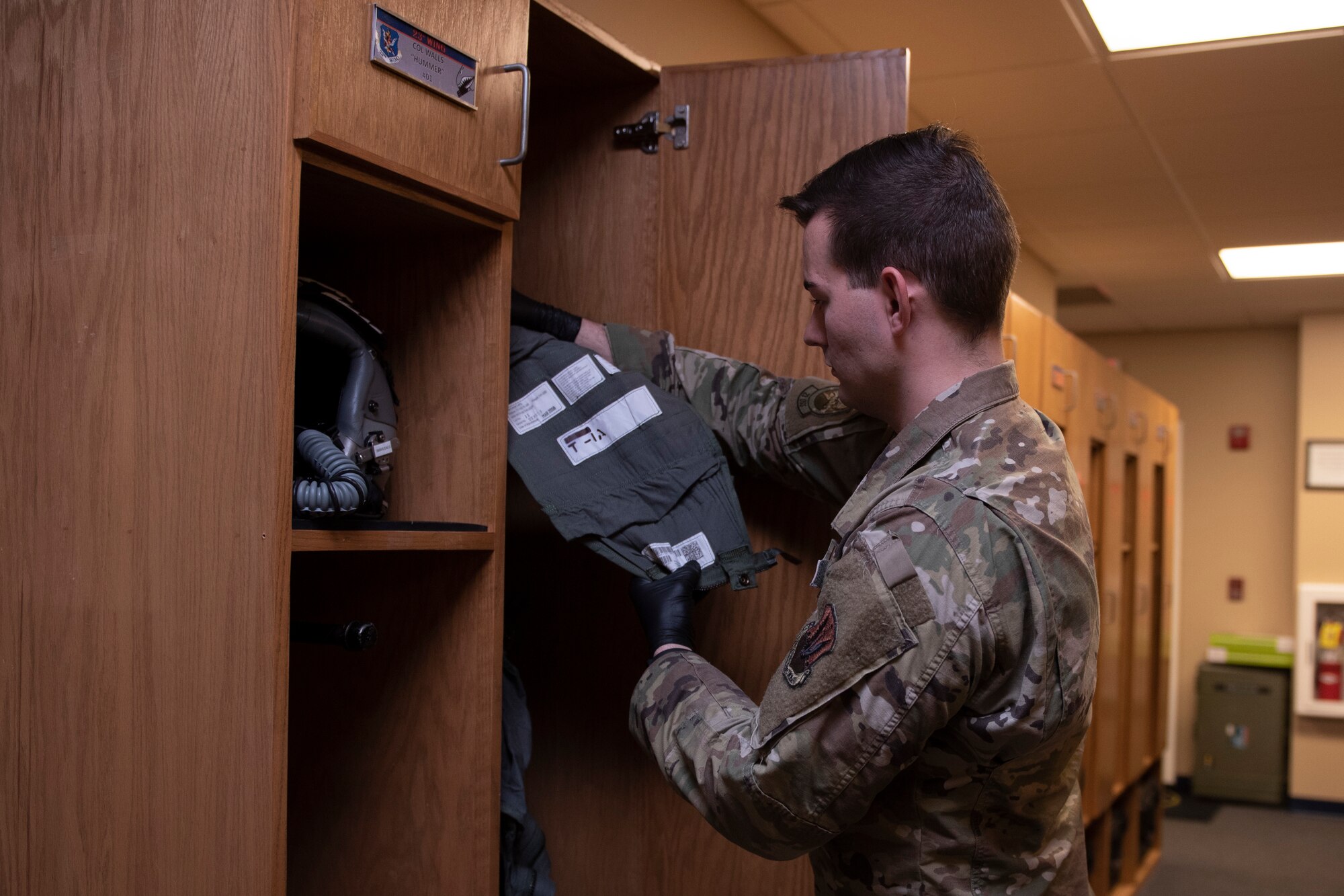 A photo of an Airman placing an Anti-G suit in a locker after an inspection.