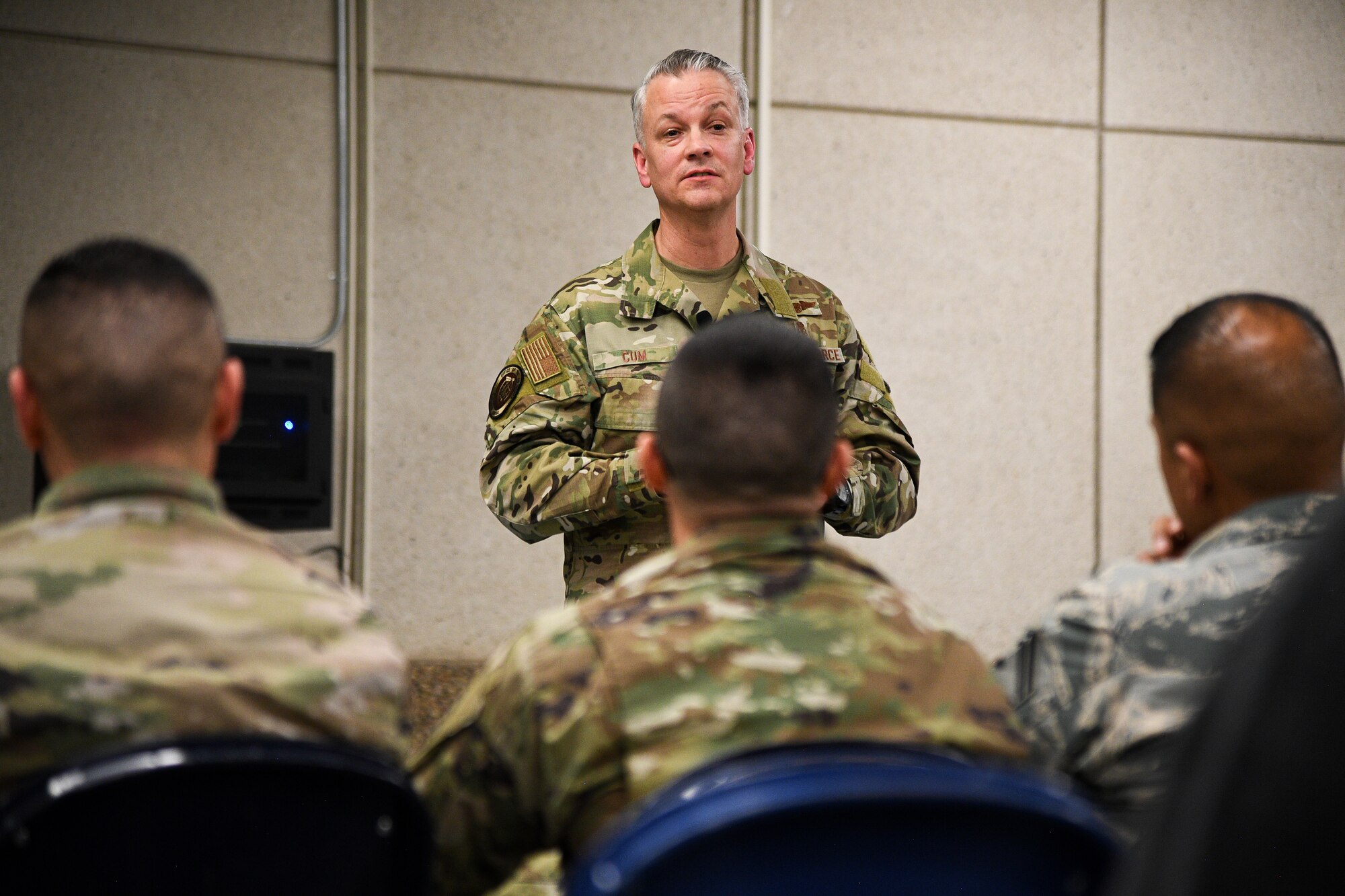 Chief Master Sgt. Cum stands in front of an audience during a town hall meeting with Hill AFB's military, civilian and contractor medical personnel.