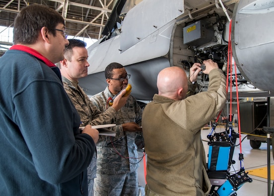 Martin Leduc, Technologies Harness Scanner engineer, Tech. Sgt. Charles Prince, 412th Logistics Test Squadron, Staff Sgt. Marcell Pemberton, 412th MXLS, and Staff Sgt. Jocko Hammond, 412th Aircraft Maintenance Squadron, gather baseline readings from an F-16 avionics wire bundle using a hand-held multi-meter at Edwards Air Force Base, California, Feb. 4. (Photo by Giancarlo Casem)