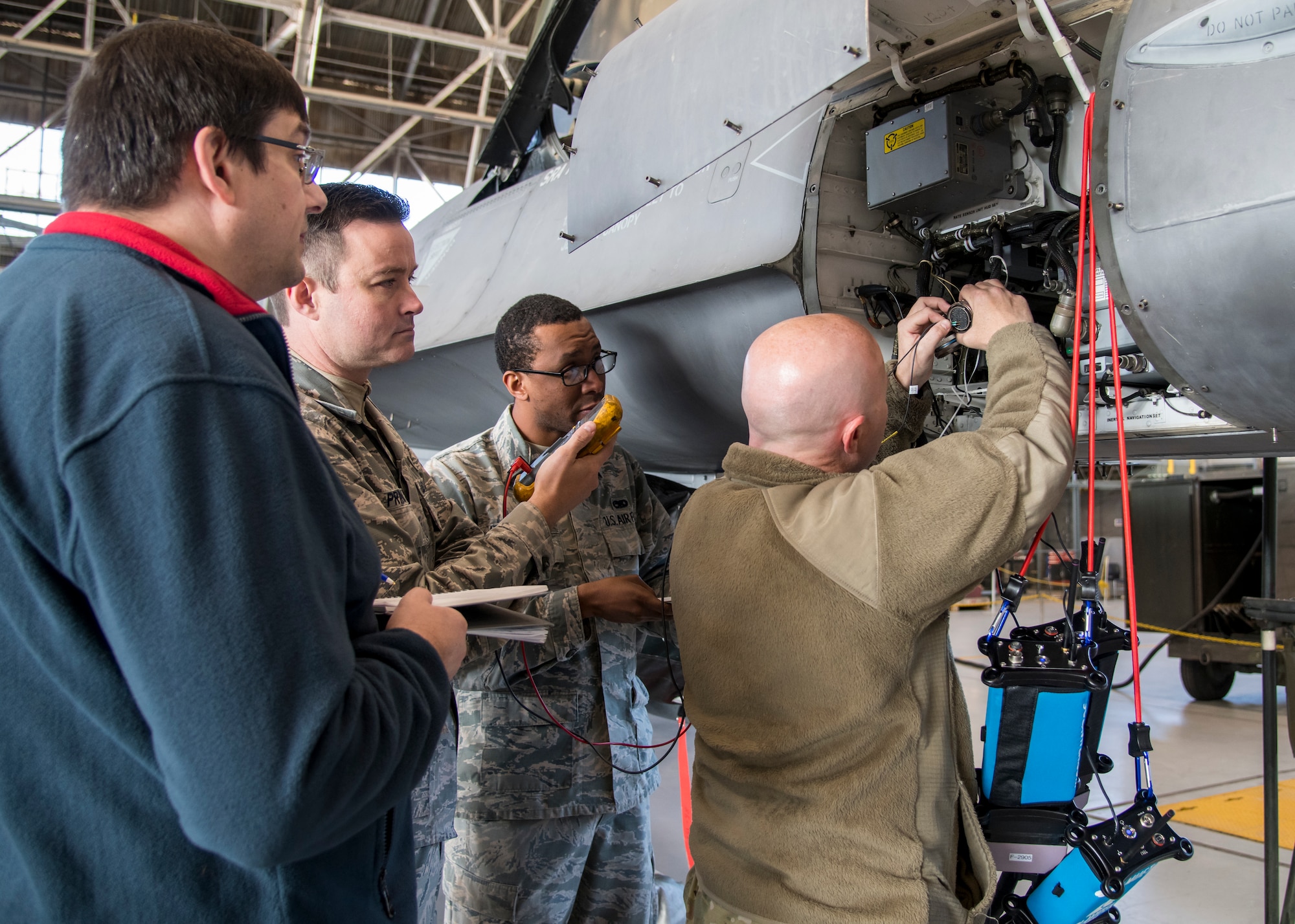 Martin Leduc, Technologies Harness Scanner engineer, Tech. Sgt. Charles Prince, 412th Logistics Test Squadron, Staff Sgt. Marcell Pemberton, 412th MXLS, and Staff Sgt. Jocko Hammond, 412th Aircraft Maintenance Squadron, gather baseline readings from an F-16 avionics wire bundle using a hand-held multi-meter at Edwards Air Force Base, California, Feb. 4. (Photo by Giancarlo Casem)