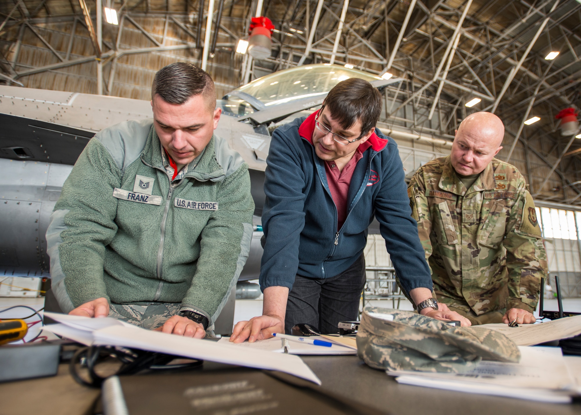 Tech. Sgt. Alex Franz, 412th Aircraft Maintenance Squadron, Martin Leduc, Technologies Harness Scanner engineer, and Staff Sgt. Jocko Hammond, 412th AMXS, review F-16 electrical wiring schematics during an Advanced Mobile Universal Electrical Tester, or AMUET, testing session at Edwards Air Force Base, California, Feb. 4. (Photo by Giancarlo Casem)