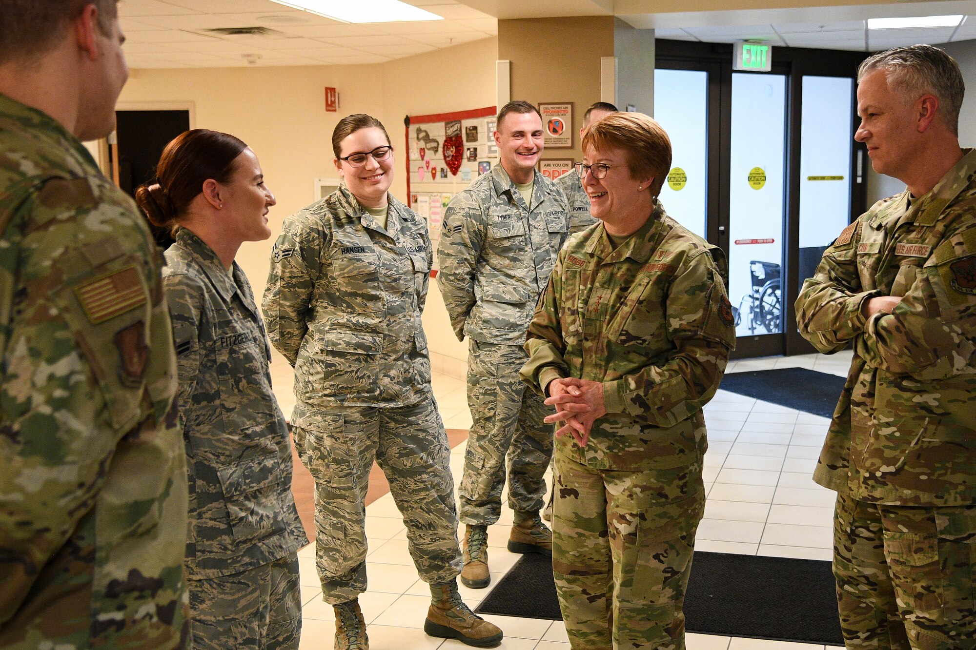 Lt. Gen. Hogg (center) talks with Airman 1st Class Sofia Fitzgerald (left) in the lobby of the medical clinic while others watch on.