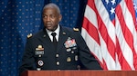 African-American man in Army dress uniform stands at a podium in front of the U.S. flag.