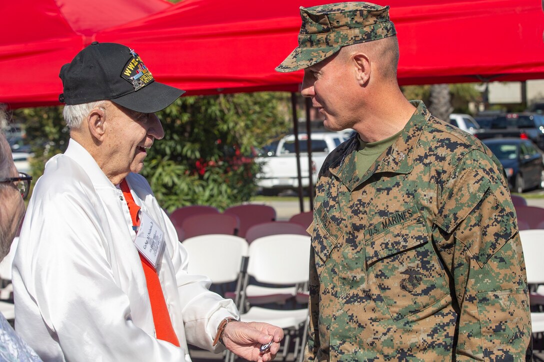 Al Nelson, Jr, a veteran of the Battle of Iwo Jima, displays a challenge coin to U.S. Marine Col. Jeffery Holt, the deputy commander of Marine Corps Installations West, Marine Corps Base Camp Pendleton, during the 75th Anniversary of the Battle of Iwo Jima Commemoration tour on Camp Pendleton, California, Feb. 13, 2020. The veterans who toured were part of the Iwo Jima Commemorative Committee. The veterans were given a tour of the base, a static display of modern Marine Corps technology and equipment, and a concert performed by the 1st Marine Division Band.  (U.S. Marine Corps photo by Lance Cpl. Drake Nickels)