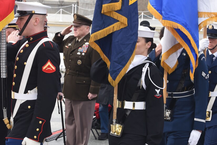 General salutes as he stands in the midst of a military color guard.