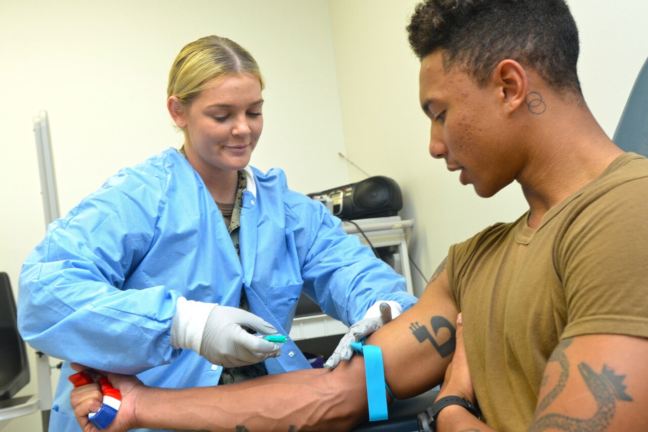 Lab technician prepares to  draw blood from patient.