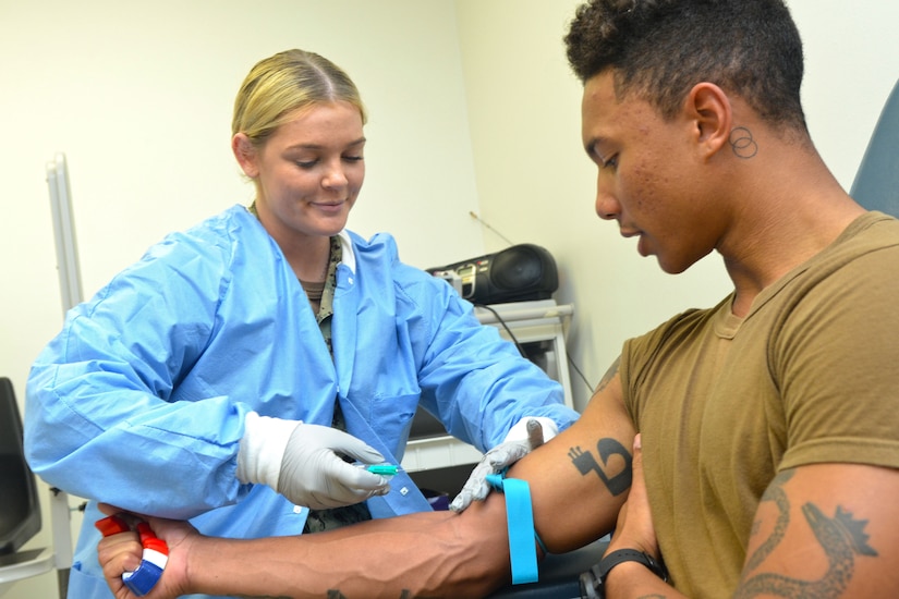 Lab technician prepares to  draw blood from patient.