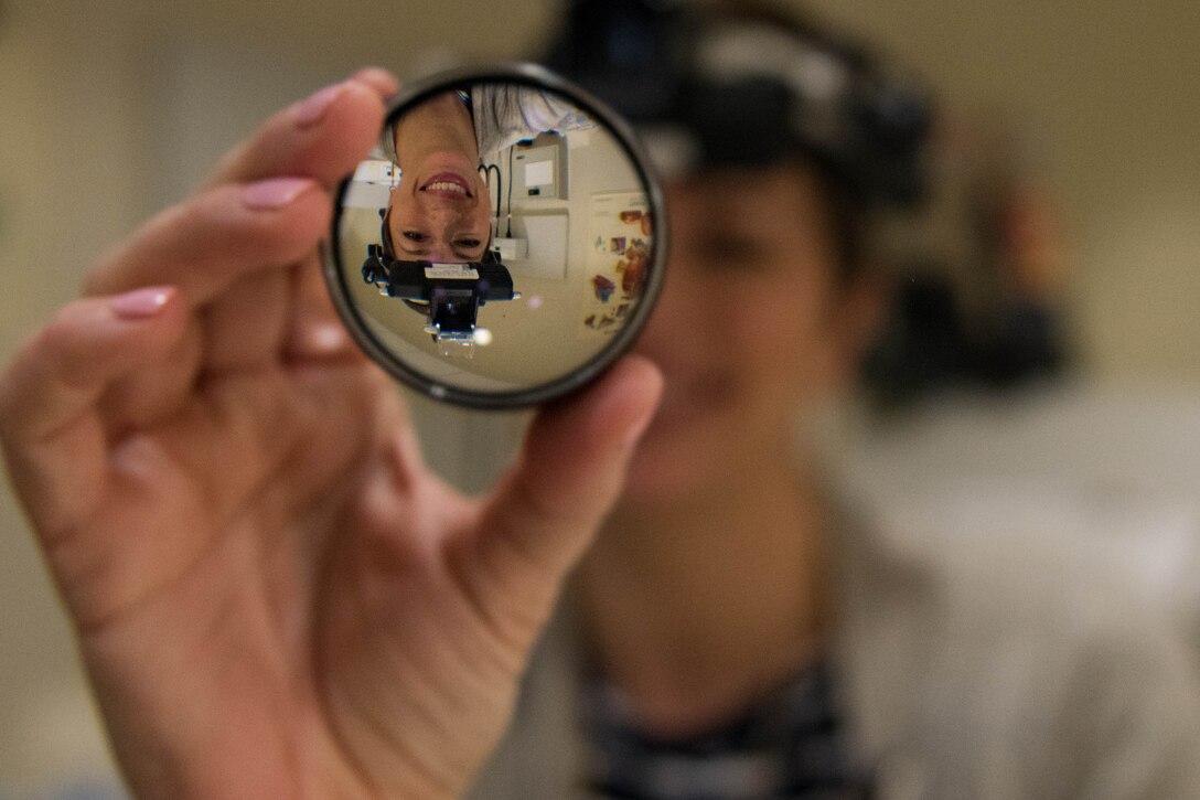 Optometrist looks into hand-held lens.